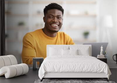 Portrait of positive black guy working on laptop Wall mural