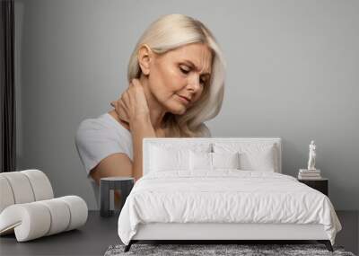 Portrait of upset mature woman suffering neck pain and strain Wall mural