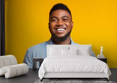 Portrait of young laughing african american guy over yellow background Wall mural