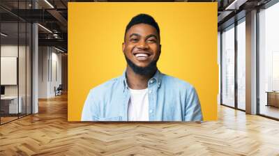 Portrait of young laughing african american man over yellow background, copy space Wall mural