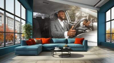 Positive african american businessman driving car, front panel shot Wall mural