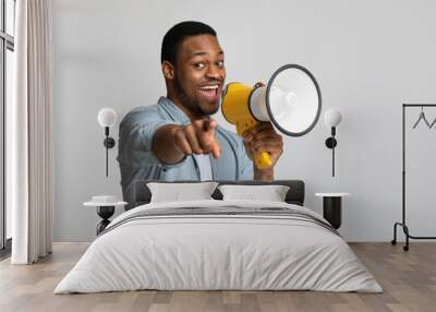 Positive african guy shouting in megaphone over grey background Wall mural