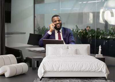 Positive black manager working on computer, having phone conversation Wall mural