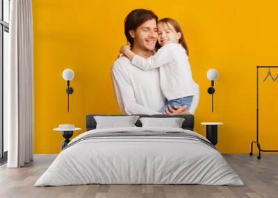 Positive father and daughter posing together on yellow background Wall mural