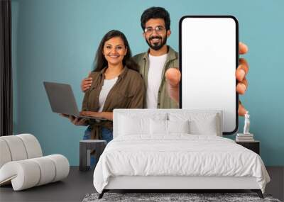 Positive mixed race couple using laptop, showing big phone, mockup Wall mural