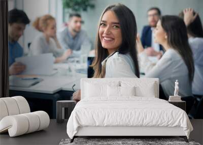 Positive secretary smiling to camera during meeting Wall mural