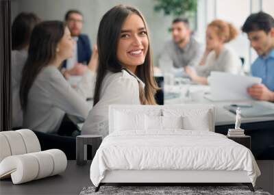 Positive secretary smiling to camera during meeting Wall mural