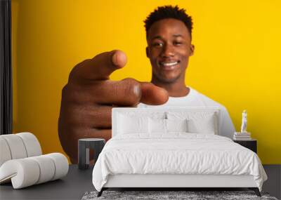 Positive young black man smiling and pointing index finger at camera, showing big gesture on orange background Wall mural