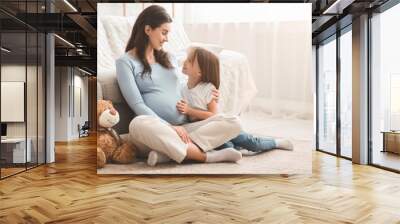 Pregnant mother and her happy daughter playing together Wall mural