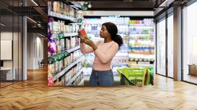 pretty african american woman choosing groceries at supermarket, shopping for food, buying products  Wall mural