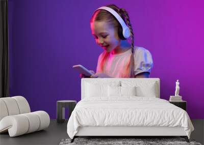 Pretty preteen blonde girl using smartphone and headphones, copy space Wall mural