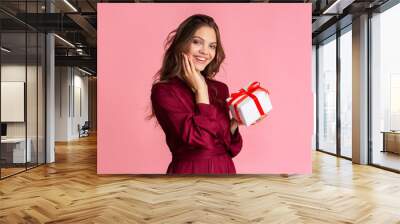 Pretty young woman holding gift box and looking at camera Wall mural