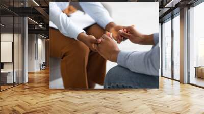 Professional compassion. Psychotherapist supporting her depressed male patient, holding his hand indoors, closeup Wall mural