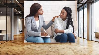 Psychotherapist comforting sad female patient during therapy session in office Wall mural