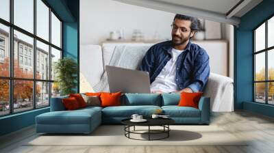 Remote Work. Handsome Eastern Freelancer Guy Working With Laptop At Home Wall mural