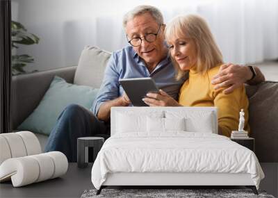 Retired Couple Using Digital Tablet Computer Together Sitting At Home Wall mural