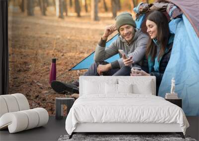 Romantic couple camping outdoors, sitting in tent and talking Wall mural