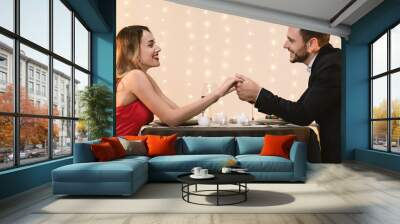 Romantic couple holding hands, celebrating their anniversary on date in restaurant Wall mural