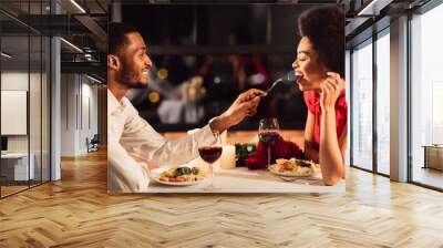 Romantic Date Concept. African American Man Feeding Girlfriend During Dinner Celebrating Anniversary In Restaurant Wall mural