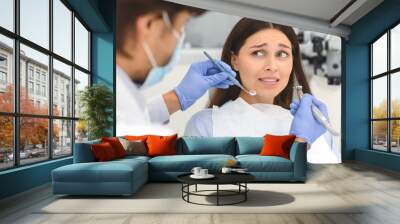 Scared woman at dental office, looking panickly at dentist Wall mural