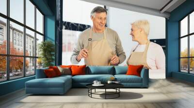 Senior Husband And Wife Cooking Together Standing In Kitchen Wall mural