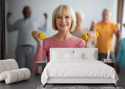 Senior lady doing strength building workout with dumbbells Wall mural