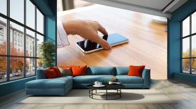 Side view shot of female hand holding smart phone Wall mural