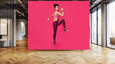 Slender fitness afro girl making work out, warming up body before training over red studio background Wall mural