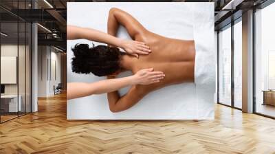 Slim black woman receiving full body massage at modern spa Wall mural