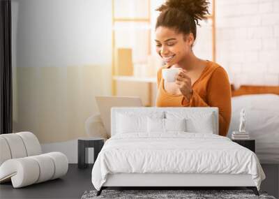 Smiling Afro Woman Using Laptop Having Coffee Sitting In Bedroom Wall mural