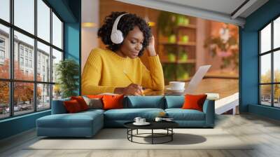 Smiling black girl with headset studying online, using laptop Wall mural