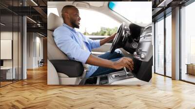 Smiling black man driving new car in city Wall mural