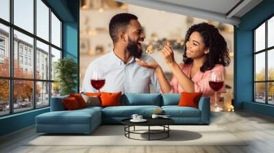 Smiling black woman feeding her man on a date Wall mural