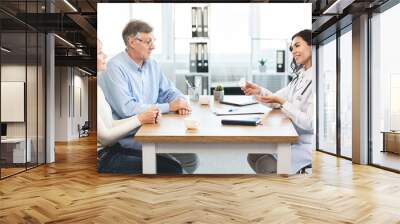 Smiling brazilian nurse giving pills to mature patients Wall mural