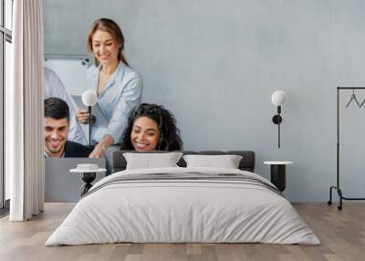 Smiling Coworkers Working Together On One Laptop In Modern Office Wall mural