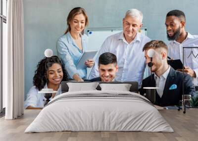 Smiling Coworkers Working Together On One Laptop In Modern Office Wall mural