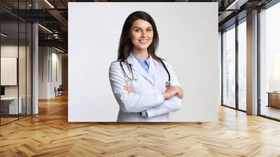 Smiling Female Doctor Standing Crossing Hands Over White Background Wall mural