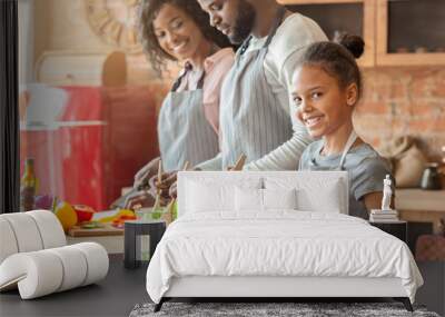 Smiling girl helping parents cooking dinner in kitchen Wall mural