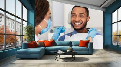 smiling guy in dentist chair looking with trust at doctor Wall mural