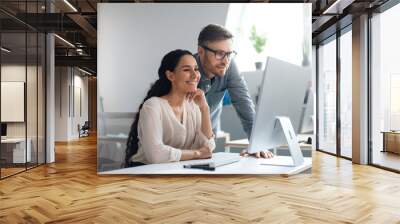 Smiling male and female employees discussing business project, using computer at company office, copy space Wall mural