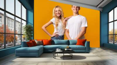 Smiling millennial couple posing over yellow background Wall mural