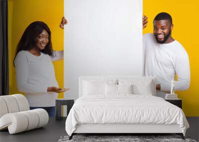 Smiling pregnant afro couple showing empty advertising board Wall mural