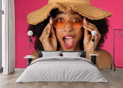 Smiling shocked cute young african american curly woman in sunglasses and hat with open mouth Wall mural