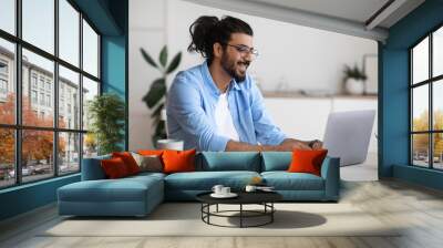 Smiling western freelancer guy working on laptop at home office Wall mural