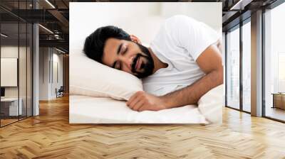 Smiling Young Indian Man Sleeping Calmly In Comfortable Bed At Home Wall mural