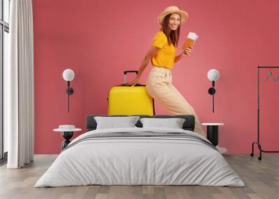 Smiling young woman in summer clothes leaning on luggage Wall mural