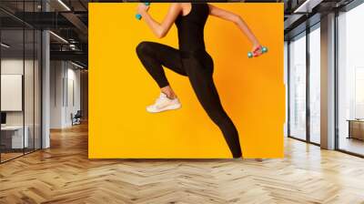 Sporty Millennial Girl Jumping With Dumbbells On Yellow Background, Studio Wall mural