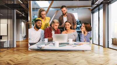 Startup concept. Designer team using laptop in office Wall mural