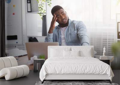 Stressed african american employee drinking alcohol in office Wall mural