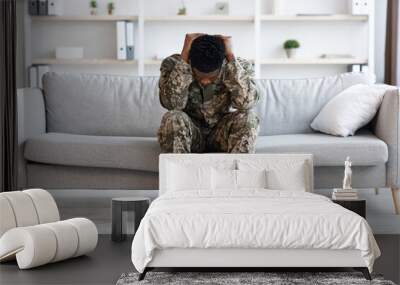 Stressed african american soldier in military uniform sitting on couch Wall mural